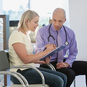 Young Caucasian woman with her doctor signing a form