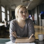 Young Caucasian woman with her arms crossed leaning on a table