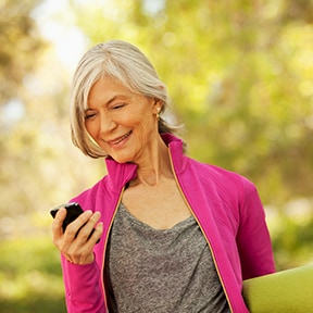 Older woman outdoors in warmup jacket looking at mobile phone