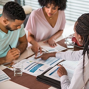 African-American representative reviewing paperwork with young African-American couple