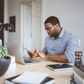 African-American man at home on his laptop and a handheld device
