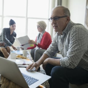 Older couple meeting a woman in living room with the husband looking at laptop