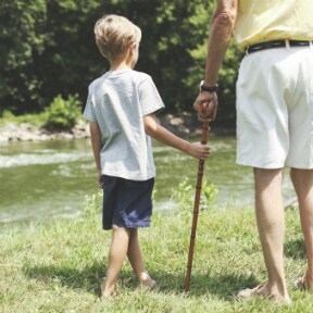 Young boy and elderly man walking beside a stream
