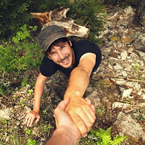 Rock climbing young man being given a hand up