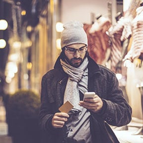 Thirty something Caucasian man outside dressed for winter looking at cellphone
