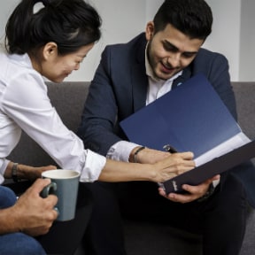 Asian-American woman signing a document with a businessman