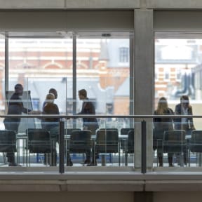 View looking into glass-walled office of businesspeople standing and shaking hands in a meeting room