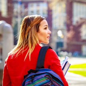 Young female in bright red jacket with backpack and holding books