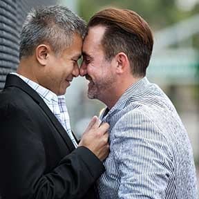Male gay couple leaning close with foreheads and noses touching
