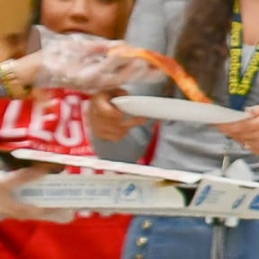 Pizza being handed out to standing people