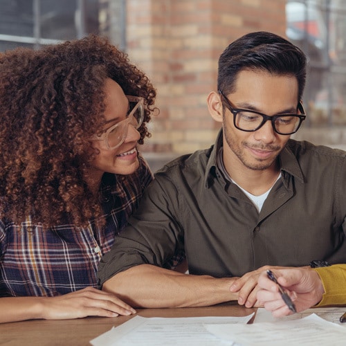 Mixed race young couple reviewing documents with someone off camera
