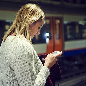 Caucasian woman looking at her phone in a subway station