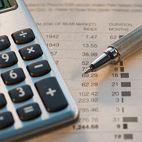 Close up of calculator, pen and stock market returns