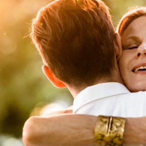 From behind, a man being hugged by a woman