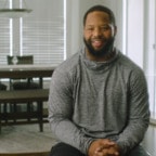 African-American man sitting, with a table in the background