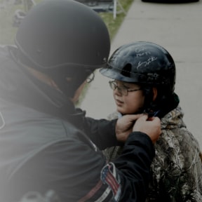 Adult helping a child with their riding helmet