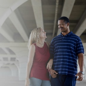 Caucasian woman smiling with her arm through the arm of an African-American man