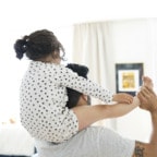 Young man with daughter on shoulders looking at a tablet with her