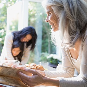 Grandmother looking up recipe with daughter and granddaughter in background